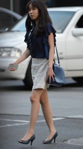 娇小的上班女郎脚踩高跟手持苹果手机走路上班