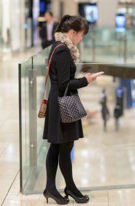 穿黑色裤袜高跟鞋在电影院边等人的年轻女人