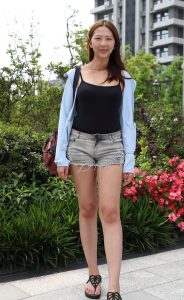 在小区院内穿牛仔热裤秀长腿的美女