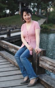 成熟风韵的大姐穿V领衫牛仔裤在湖边拍照