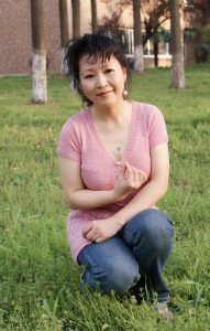 成熟风韵的大姐穿V领衫牛仔裤在湖边拍照